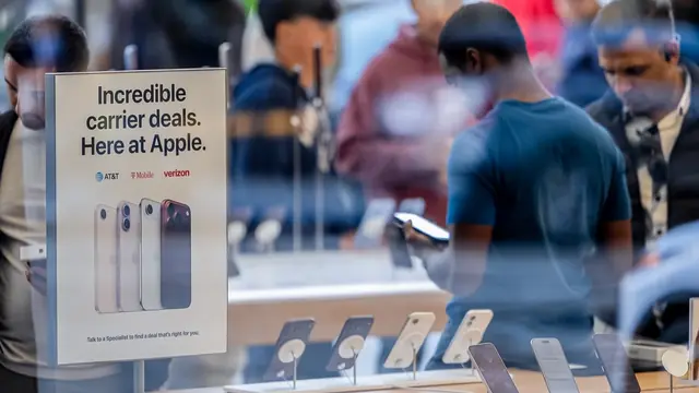 Shoppers inside an Apple Store next to a display sign reading 'Incredible carrier deals. Here at Apple.'