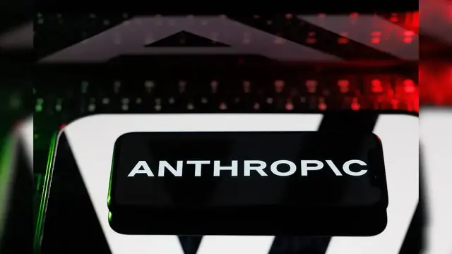 The Anthropic wordmark on a phone screen, in front of a blurred keyboard lit red and green